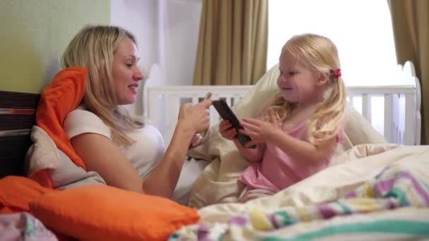 Mom and baby use smartphones at home in the bedroom. — Stock Video