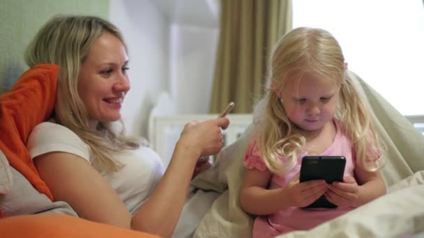 Mom and baby girl with smartphones at home. — Stock Video