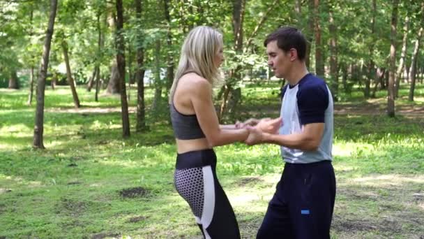 Una mujer está entrenando en un parque con un entrenador de artes marciales, cámara lenta . — Vídeo de stock