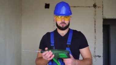 Elinde çekiç matkabı olan ciddi bir inşaat işçisinin portresi..