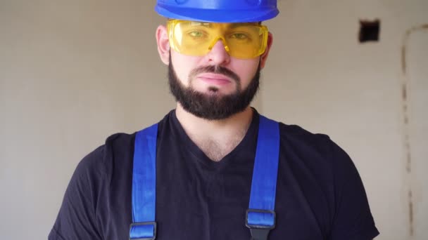 Portret van een positieve mannelijke bouwer met een baard en een helm. — Stockvideo