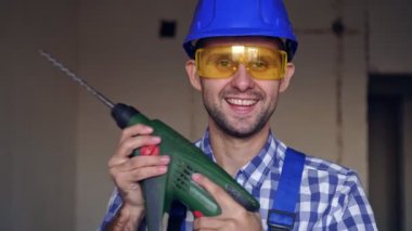 Elektrikli çekiç matkabıyla mutlu bir erkek inşaatçının portresi..