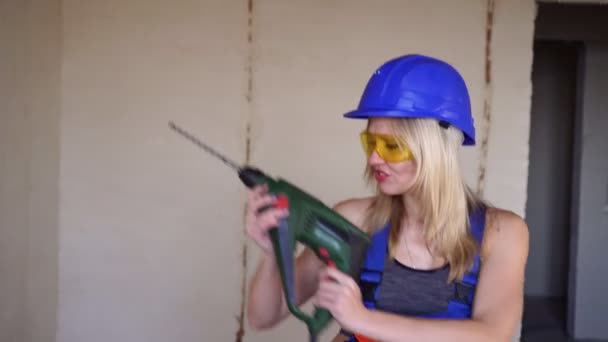 Hermosa mujer constructora bailando con un taladro de martillo eléctrico . — Vídeo de stock