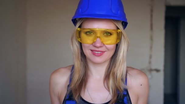 Portrait of a young beautiful builder woman. Cute girl builder in a helmet. — Stock Video