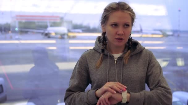 An excited female passenger at the airport looks at her watch — Stock Video