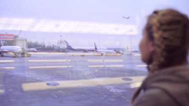 Havaalanında bir kadın uçağın kalkışını izliyor.