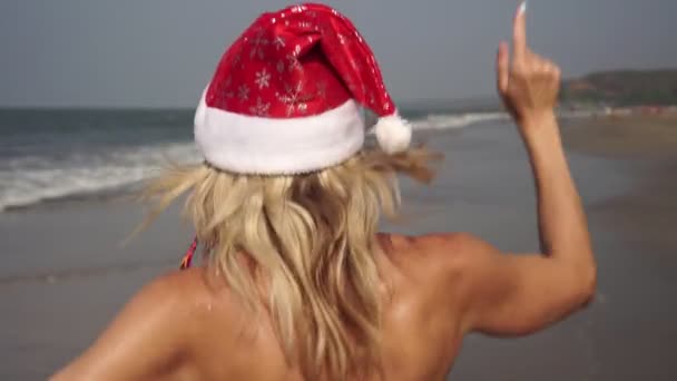 Bella donna che balla sulla spiaggia in costume da Babbo Natale. Capodanno e Natale ai tropici in riva al mare — Video Stock