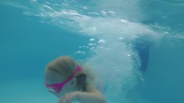 Un niño pequeño aprende a nadar en la piscina. Una chica está nadando bajo el agua — Vídeos de Stock