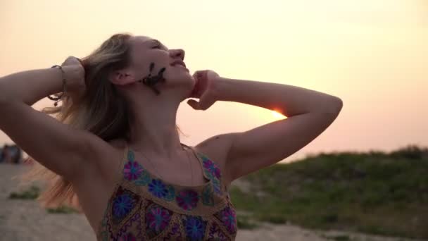 해변에서 일몰을 하고 있는 아름다운 금발의 젊은 여인의 사진. — 비디오