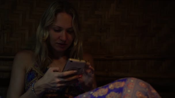 Женщина в темноте пользуется смартфоном — стоковое видео