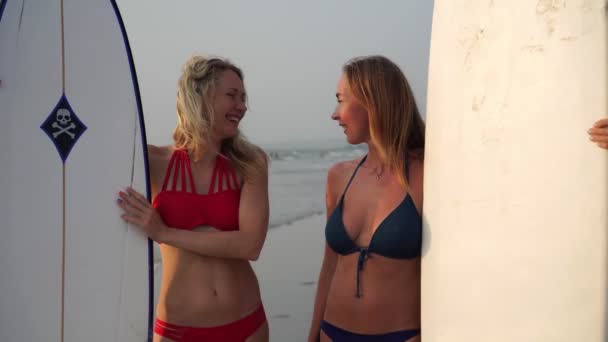 Две красивые молодые женщины с серфингом на фоне моря — стоковое видео