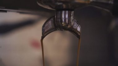 Profesyonel bir kahve makinesinin musluğundan koyu kahve dökülür.