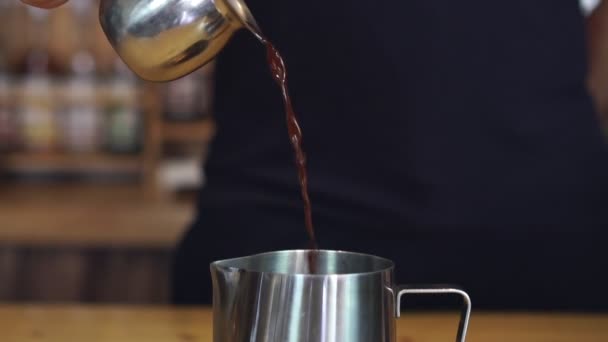 Barman giet zwarte koffie in een metalen kan. Trage beweging van het maken van koffie — Stockvideo