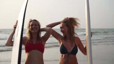 Denize karşı bikinili iki seksi kadın sörfçü, ağır çekim..
