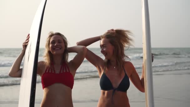 Twee sexy vrouwen surfers in bikini 's tegen zee achtergrond, slow motion. — Stockvideo