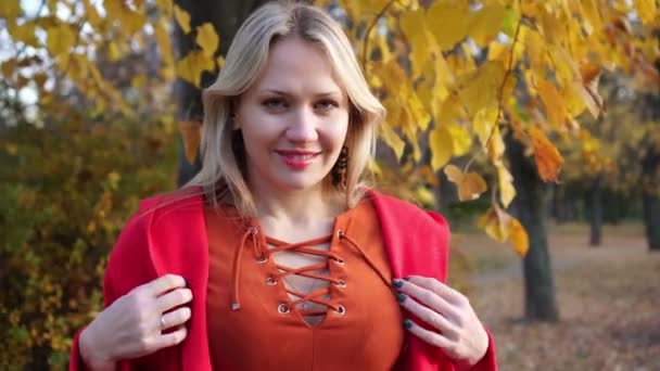 Young woman in a red coat on a background of yellow autumn leaves. — Stock Video
