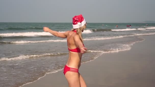 Beautiful woman in a swimsuit celebrates New Year and Christmas on the sea beach — Stock Video