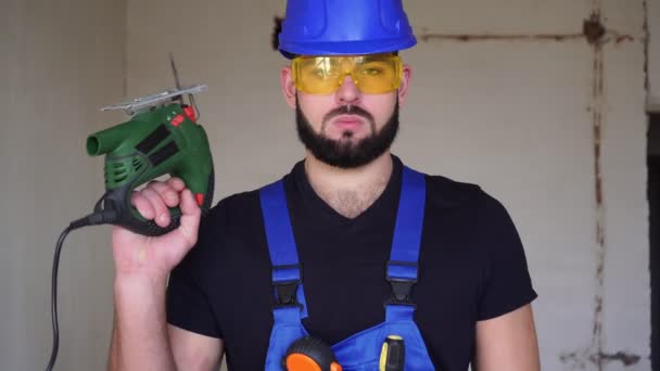 Retrato de un constructor con un rompecabezas eléctrico. Trabajador masculino con sierra eléctrica — Vídeo de stock