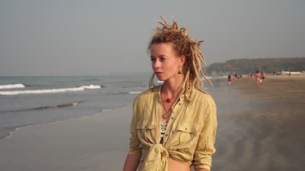 Rasta saçlı genç bir kadın deniz sahilinde yürüyor. — Stok video