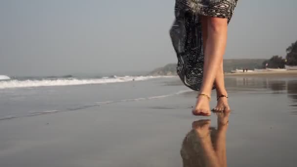 Dişi bacakları kumlu sahil boyunca uzanıyor. Bir kadın kumsalda yürüyor.. — Stok video