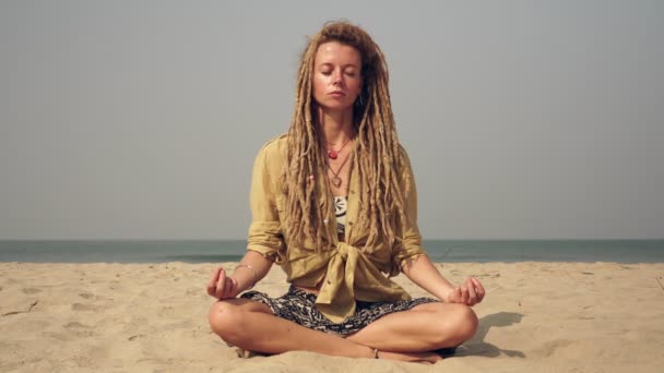 Молода красива дівчина практикує йогу на пляжі. Жінка з дредлоками медитує . — стокове відео