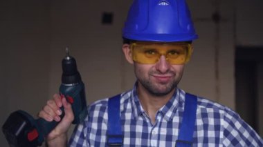 Elektrikli tornavidayla mutlu bir erkek müteahhit. Bir erkek işçinin portresi