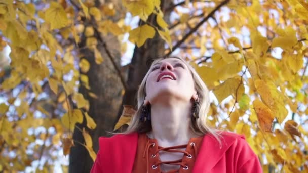 Schöne Frau im Park wirft Herbstblätter in Zeitlupe. — Stockvideo