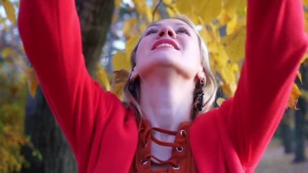 Het meisje in het park geeft herfstbladeren op. Herfst, portret van een mooie vrouw. — Stockvideo