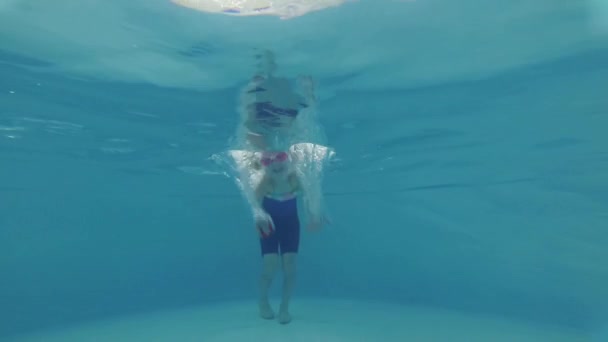 Barnflicka i en pool lär sig att dyka och simma med en tränare — Stockvideo