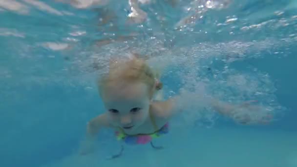 Klein kind meisje leert zwemmen onder water in een zwembad — Stockvideo