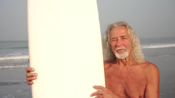 Portret van een oude volwassen man met een surfplank. Actieve ouderdom — Stockvideo