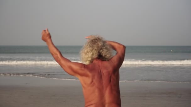 Old man goes in for sports on the beach. Athletic adult male senior citizen is training on the beach — Stock Video