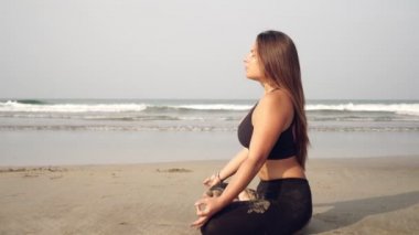 Plajda yoga yapan genç bir kadın deniz kenarında meditasyon yapan bir kız.