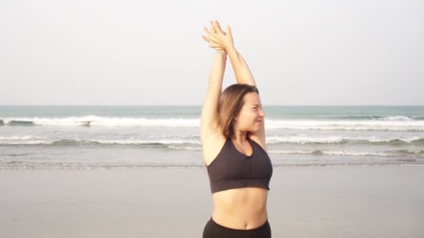 Eine junge Frau spaziert an einem Sandstrand am Meer entlang — Stockvideo