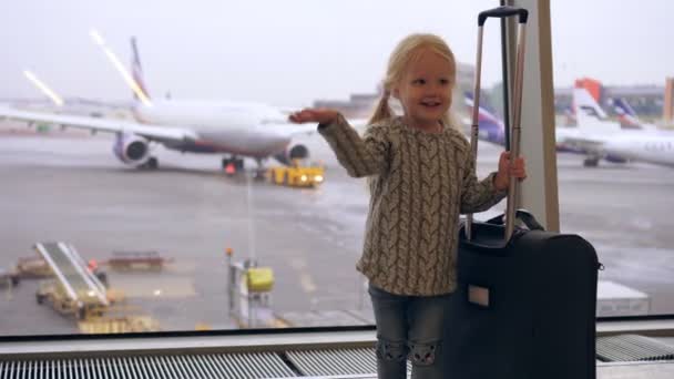 Ein Kind mit einem Koffer am Flughafen vor dem Hintergrund von Flugzeugen — Stockvideo