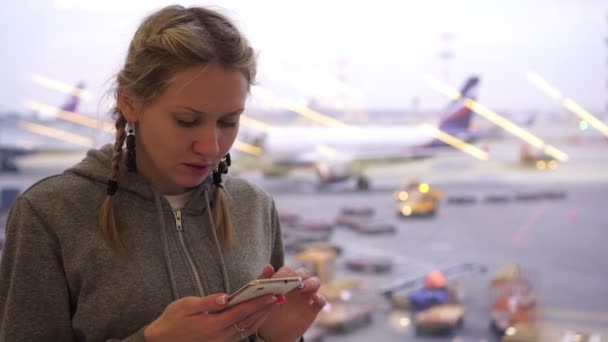 Женщина в аэропорту со смартфоном. Турист в терминале аэропорта пользуется телефоном . — стоковое видео