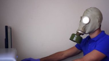 Gaz maskeli ya da solunum cihazlı bir adam evde bilgisayarla çalışıyor. Salgını önleme