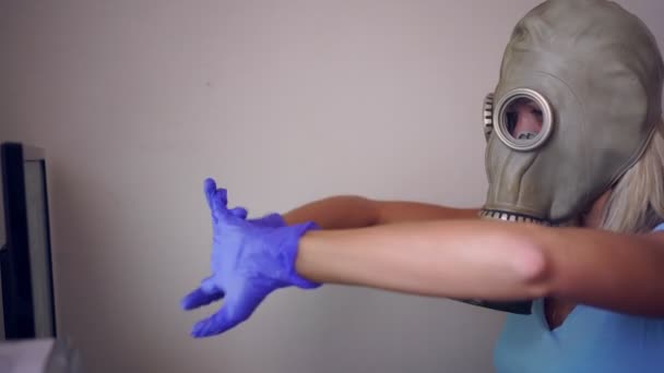 Een vrouw met een gasmasker en medische handschoenen werkt thuis op een computer — Stockvideo