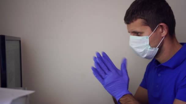 의료용 마스크를 쓰고 있는 남자는 집에서 컴퓨터로 일합니다. 격리 구역, 코로나 바이러스, 집무실 — 비디오