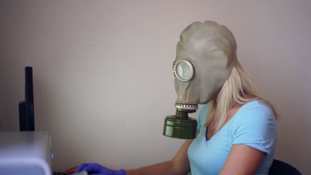 En kvinna i gasmask eller respirator arbetar hemma på en dator. Förebyggande av koronovirus — Stockvideo