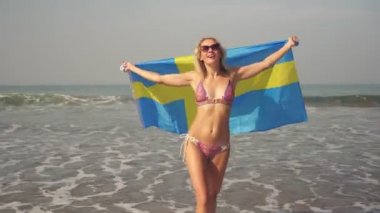 Sahilde güzel bir kadın İsveç bayrağıyla