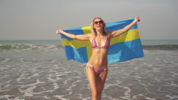 Hermosa mujer en la playa de mar con bandera sueca — Vídeos de Stock