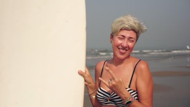 Sörf tahtası olan neşeli, olgun bir kadının portresi. Sörf yapan pozitif büyükanne. — Stok video
