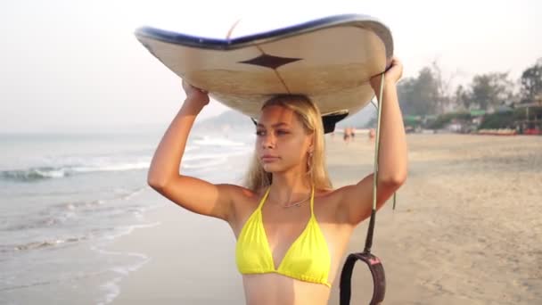 Портрет девушки-серфера на пляже с доской для серфинга — стоковое видео