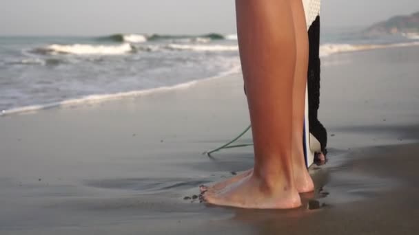 Mujer atractiva joven en un traje de baño con una tabla de surf — Vídeo de stock