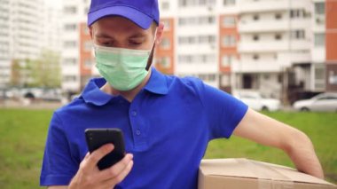 Tıbbi maskeli erkek kurye akıllı telefon kullanıyor.