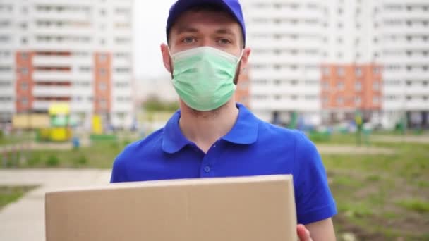 Man koerier bezorger met een medisch masker op zijn gezicht — Stockvideo