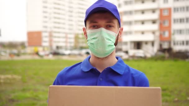 Man koerier levering man in medisch masker toont duim omhoog gebaar — Stockvideo