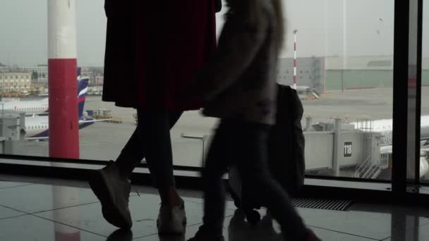 Силуэт женщины и ребенка в аэропорту на фоне окна — стоковое видео