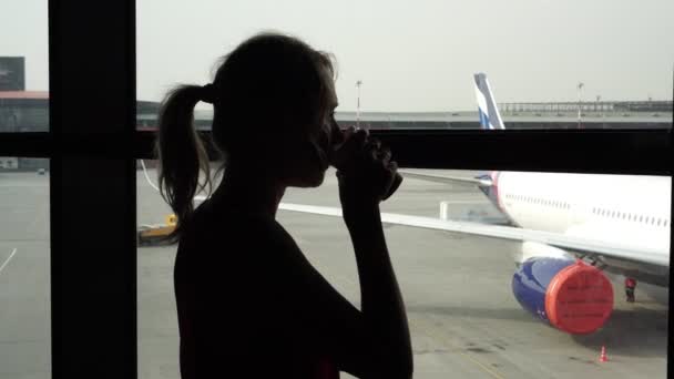 Силует жінки в аеропорту на задньому плані літака. — стокове відео